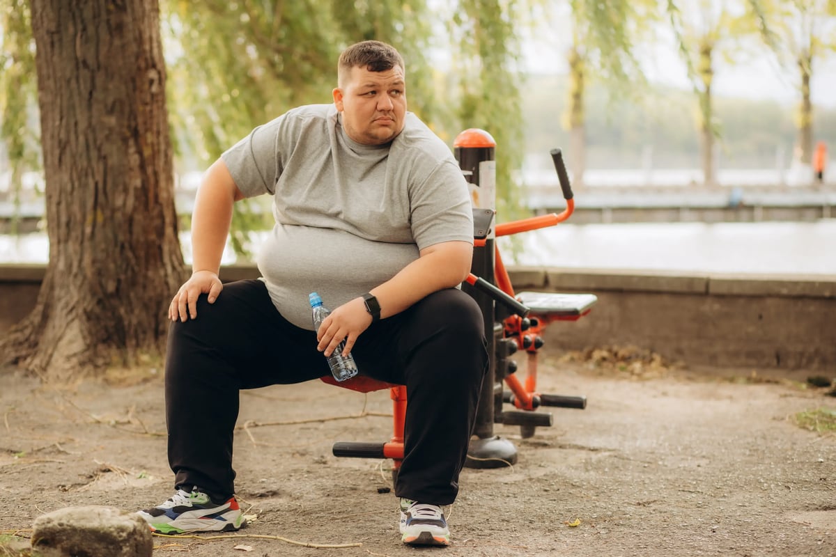 Illustrative stock photo of an adult resting beside outdoor exercise equipment; not a Leva patient