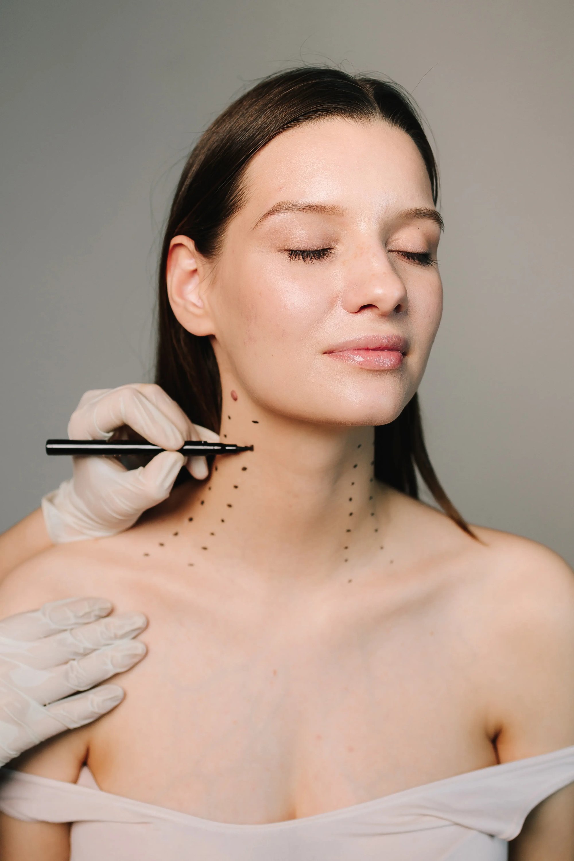 Illustrative stock photo of a gloved clinician marking neck bands on a model with a surgical pen; not a Leva patient