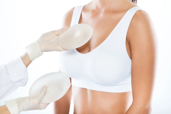 female-doctor-choosing-mammary-prosthesis-with-her-patient-white-background